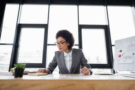African american businesswoman using calculator while working in officeの写真素材