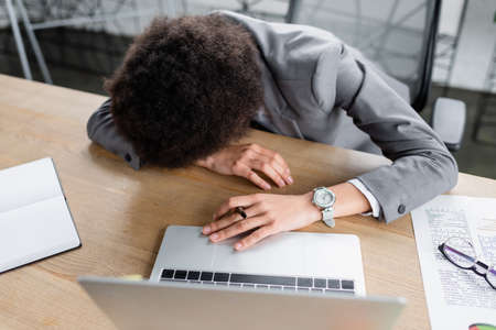 Overhead view of african american manager with pen sleeping on working table near laptop