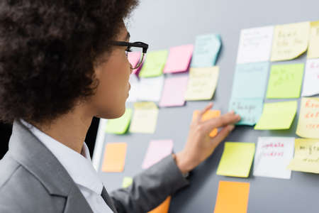 African american businesswoman standing near flipchart with sticky notes on blurred backgroundの写真素材