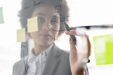 Blurred african american businesswoman writing on glass boardの写真素材