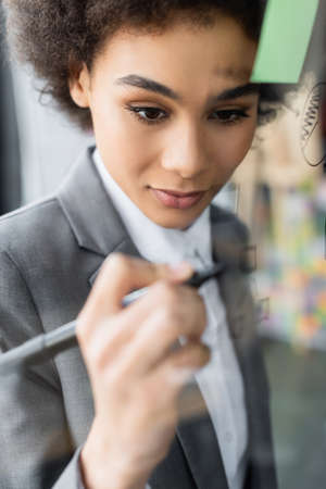 African american businesswoman drawing on blurred glass boardの写真素材