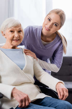 happy nurse and senior handicapped woman smiling while looking at camera