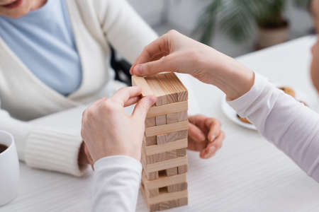 partial view of nurse playing wood blocks game with aged woman on blurred backgroundの写真素材