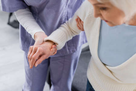 partial view of nurse supporting aged woman, blurred foregroundの写真素材