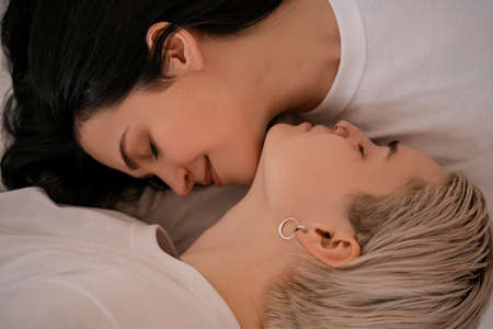 top view of lesbian couple lying in bedの写真素材