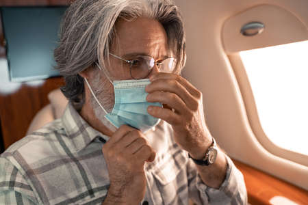 Mature man wearing medical mask in private jet