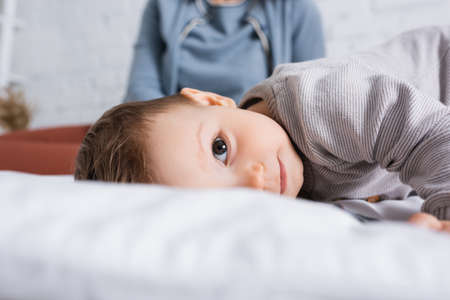 infant boy looking at camera while lying on bed