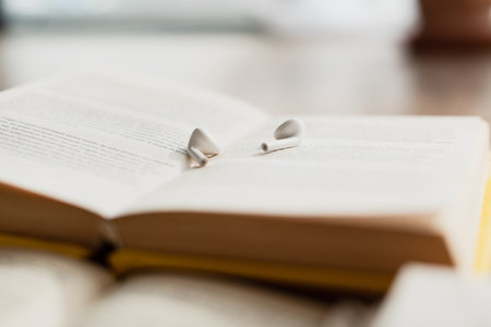 white wireless earphones on blurred book