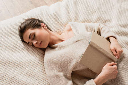 top view of young woman sleeping with book on bedの写真素材