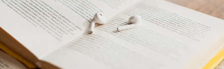 white wireless earphones on blurred book, bannerの写真素材