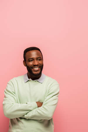 Smiling african american man with crossed arms looking at camera isolated on pinkの写真素材