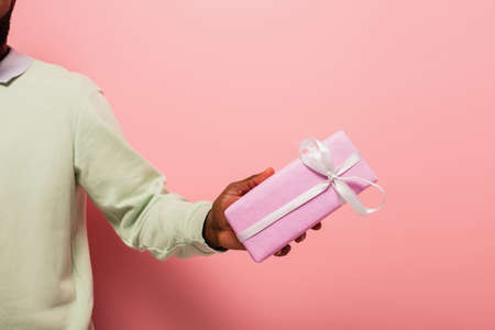 cropped view of african american man with gift box on pink backgroundの写真素材