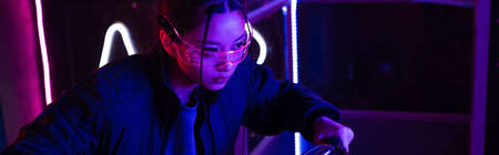 young asian woman in sunglasses near neon lighting, bannerの写真素材