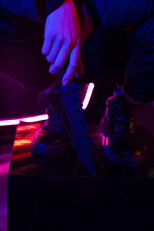 cropped view of woman in boots holding knifeの写真素材