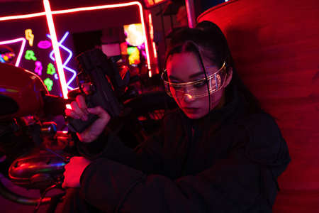 armed asian woman in sunglasses holding gun