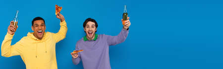 interracial friends enjoying pizza with beer isolated on blue, bannerの写真素材