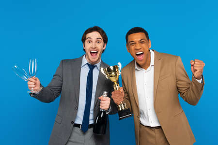 interracial friends in suits celebrating success with triumph cup, champagne and glasses in hands...