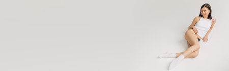 sensual young woman in white top, socks and black panties lying on gray background, bannerの写真素材