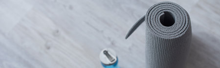 high angle view of rolled fitness mat near blurred sports bottle, bannerの写真素材