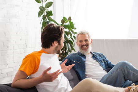 Mature man smiling at blurred son at homeの写真素材