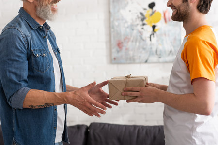Cropped view of son giving present to smiling fatherの写真素材