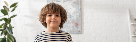Smiling boy looking at camera at home, banner