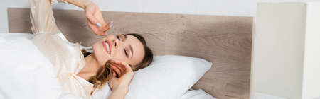 Positive woman with closed eyes lying on bed, banner