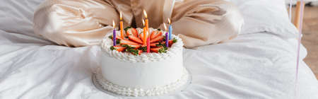 Cropped view of birthday cake with candles near woman on bed, bannerの写真素材