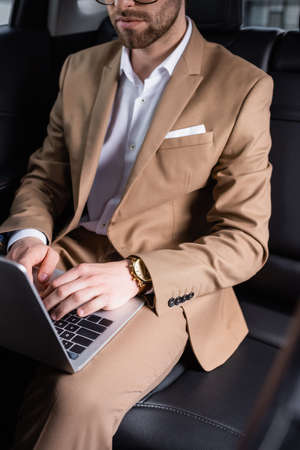 cropped view of businessman typing on laptop in carの写真素材