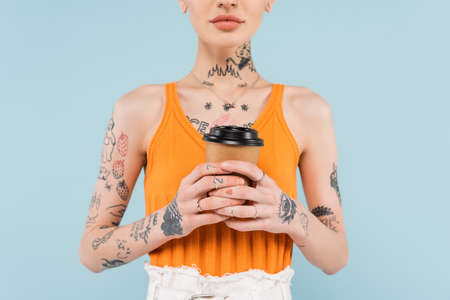 cropped view of tattooed woman holding paper cup isolated on blueの写真素材