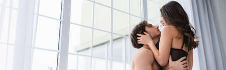 Low angle view of sexy woman in bra touching shirtless boyfriend, bannerの写真素材