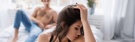 Seductive woman near blurred boyfriend in bedroom, banner
