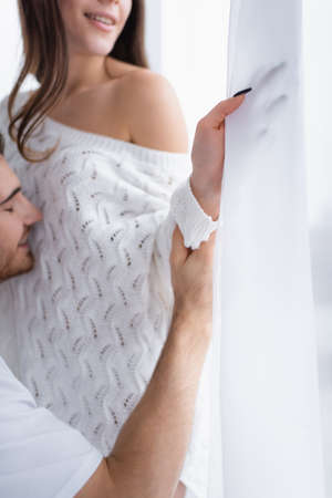 Blurred man holding hand of girlfriend near window