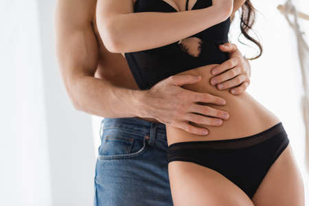 Cropped view of muscular man hugging waist of sexy woman in lingerieの写真素材
