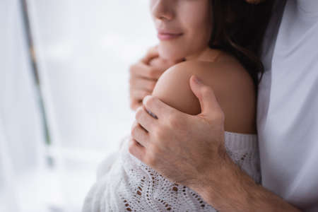 Cropped view of man touching shoulder of girlfriend in sweater