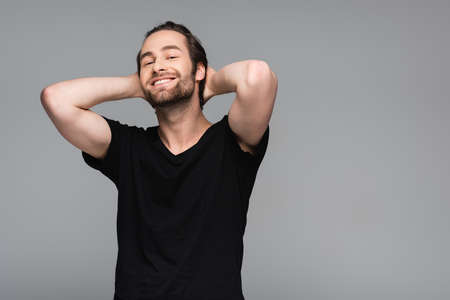 joyful bearded man in black t-shirt posing isolated on gray