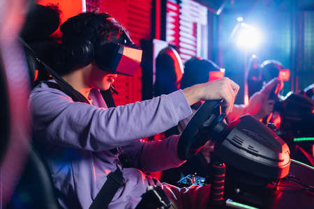 teenage boy in vr headset playing racing game on car simulatorの写真素材