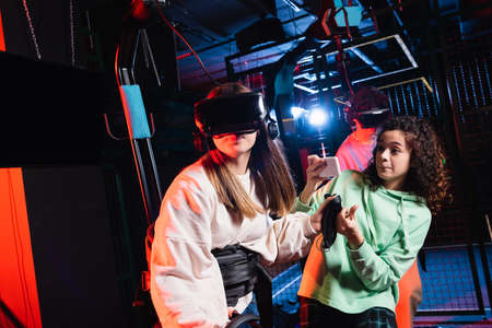 african american teenage girl taking photo of friend gaming in vr headset