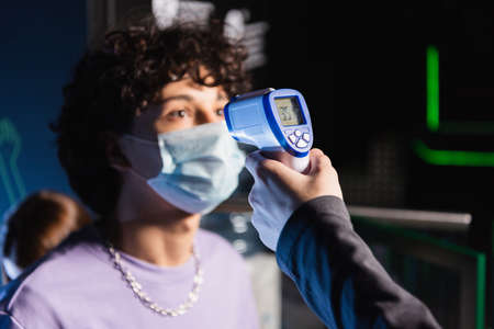selective focus of pyrometer in hand of controller near boy in safety mask