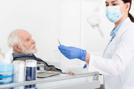 senior man having teeth treatment by dentist in latex gloves in dental clinicの写真素材