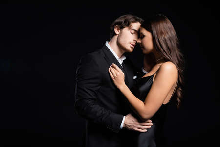 elegant young adult man and woman hugging and kissing isolated on blackの写真素材