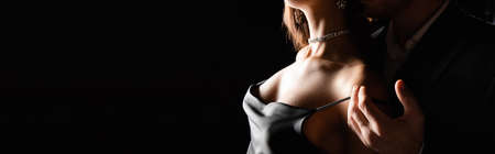 cropped view of sensual woman in silk dress with male hand on shoulder isolated on black, bannerの写真素材