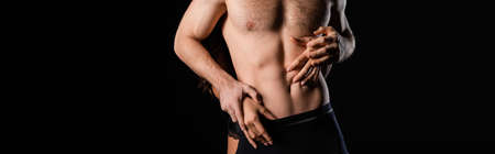 partial view of female hands touching man with shirtless torso isolated on black, banner