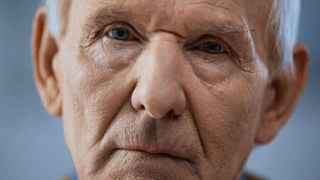 close up view of elderly man looking at camera on gray backgroundの写真素材