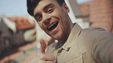 amazed man showing thumb up with blurred buildings on backgroundの写真素材