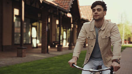 pleased man riding bicycle near buildings outside