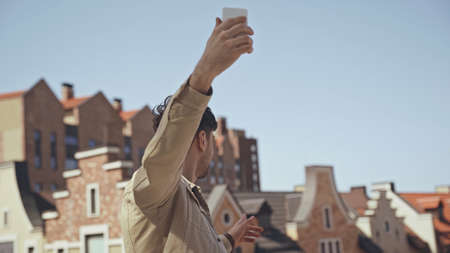 man holding smartphone while taking photo of buildingsの写真素材