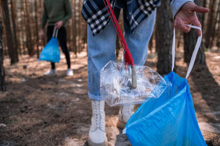 cropped view of volunteer picking up rubbish in forestの写真素材