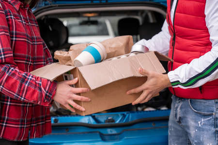 cropped view of young man and woman holding carton box with reusable cupの写真素材