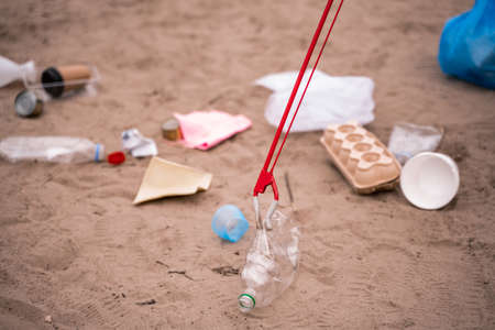 grabber with plastic bottle near stash on sandの写真素材